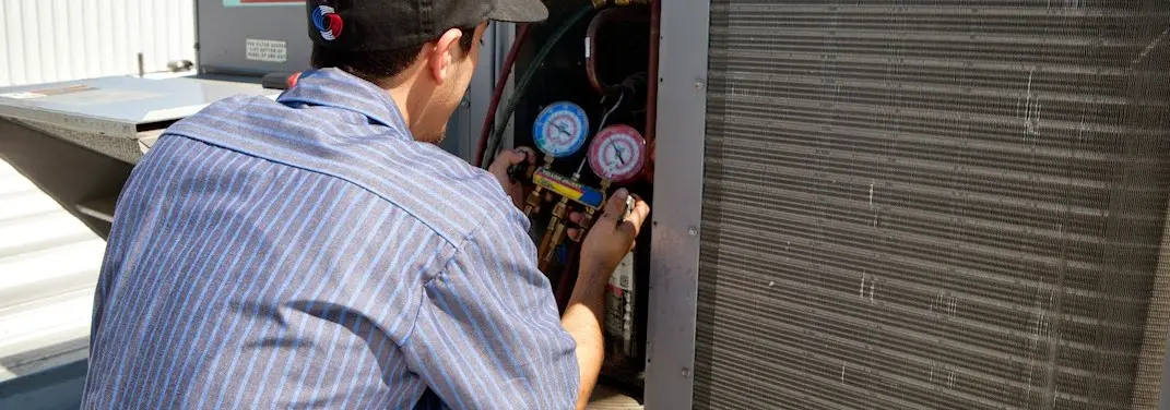 HVAC technician servicing a condenser unit in Tice