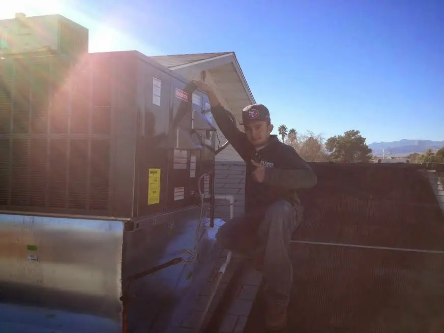 HVAC technician performing Heat Pump Repair on a rooftop unit in Tice